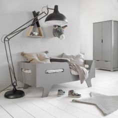 a bedroom with white walls and flooring has a gray bed frame, two lamps on the wall