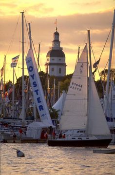 several sailboats in the water with a church in the background at sunset or dawn