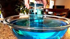 a person is pouring blue liquid into a bowl