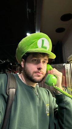 a man wearing a green hat while talking on a phone