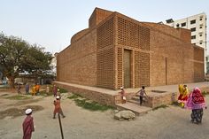 people are walking around in front of a brick building with large openings on the side