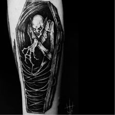 a black and white image of a skeleton in a casket tattoo on the right thigh