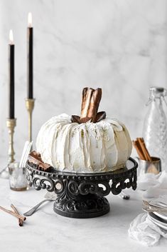 a white cake sitting on top of a black plate next to candles and other items