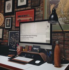 a computer monitor sitting on top of a desk next to a lamp and other items