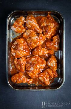 chicken wings with sauce in a pan on a black table top, ready to be eaten