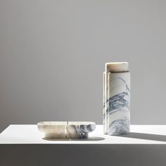 two marble vases sitting next to each other on a white counter top, one is empty