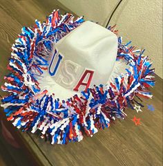 a white hat with red, white and blue streamers around it on top of a wooden table