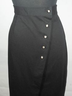 Here is a sweet vintage black knit midi skirt with a southern preppy, 1980's does 1940's style. This classic and collectible Fritzi, made in U.S.A. label, cotton polyester knit midi skirt has really great tailoring details from a tailored high waistband to the down-the-front button closure design. This cute wrap over cut knit skirt has chic style with its sleek straight cut and the vintage label says it's a **vintage size** 10 and since it's a vintage size, flat measurements are here to check yo Fitted Buttoned Formal Skirt, Formal Fitted Skirt With Buttons, Formal Fitted Pencil Skirt With Button Closure, Fitted Knee-length Skirt With Side Buttons, Formal Knee-length Skirt With Buttons, Formal Black Skirt With Button Closure, Fitted Midi Skirt With Buttons, Classic Formal Skirt With Buttons, Classic Knee-length Skirt With Buttons