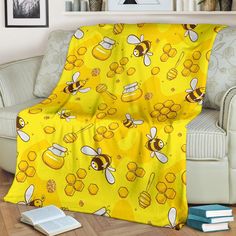 a yellow blanket with bees and honeycombs on it sitting in front of a couch