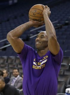 a man holding a basketball in his right hand while wearing a purple shirt with the word lakers on it