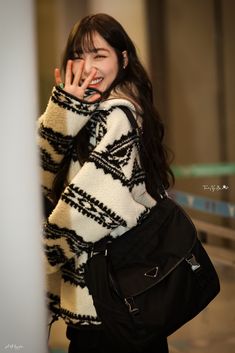 a young woman is smiling and holding her hand up to her face as she walks down the street