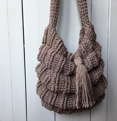 a crocheted bag hanging on a white door with a tasseled handle