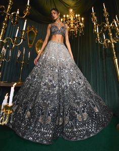 Step into refined elegance with zaahira, a statement lehenga set that captivates with its tonal ombre detailing on the lehenga skirt. Wrapped in effortless shades of nude and black, it showcases exquisite silver and black cut dana alongside delicate floral mesh. The blouse is beautifully highlighted with black teardrop embellishments gracing the silhouette's edge, infusing an air of regal drama. Paired with a net dupatta, this ensemble is a perfect blend of sophistication and bold style, making Ombre Lehenga, Shades Of Nude, Lehenga Skirt, Family Legacy, Black Ombre, Net Dupatta, Bold Style, Timeless Treasures, Bold Fashion