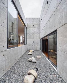 an empty courtyard with rocks and gravel in front of the windows, along with large glass doors