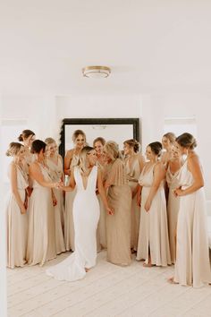 a group of women standing next to each other in front of a white wall with a mirror