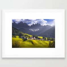 a landscape with mountains and houses in the foreground is framed by a white frame