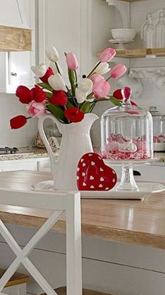 a vase filled with pink and white flowers on top of a wooden table in a kitchen