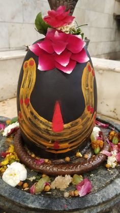 a decorative vase with flowers on it sitting on top of a stone slab in front of a wall