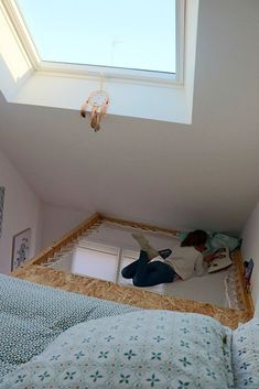 a person laying on top of a bed in a room with a skylight above