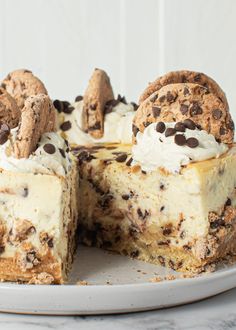 a cheesecake with chocolate chip cookies on top is cut in half and sits on a plate