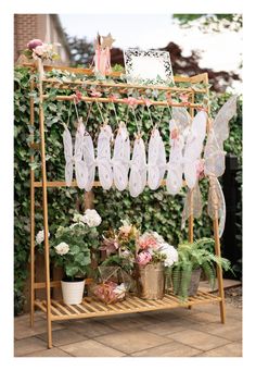 a potted plant stand with flowers and angel wings hanging from it's sides