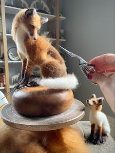 a person is holding scissors over a fake fox on top of a piece of bread