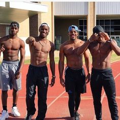 four shirtless men standing on a tennis court