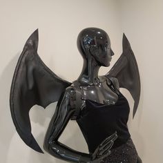 a mannequin dressed in black and silver with an elaborate bat wing on it's back