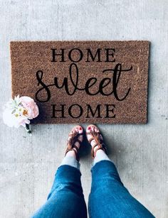 a person standing in front of a door mat that says home sweet home