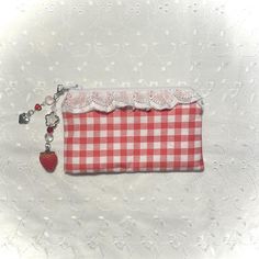 a red and white gingham purse with a heart charm hanging from it's side