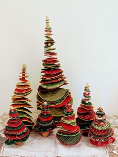 a group of small christmas trees sitting on top of a doily covered tablecloth