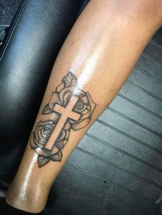 a cross and roses tattoo on the leg