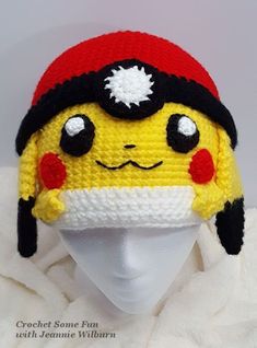 a crocheted hat with a pikachu face on it, sitting on top of a mannequin's head