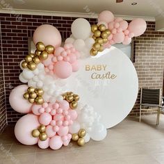 a baby shower balloon arch with gold and pink balloons