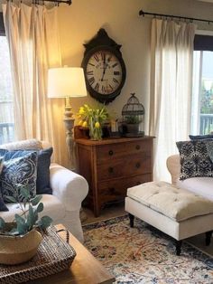 a living room filled with furniture and a clock mounted to the wall above it's windows