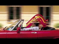 a man in a red convertible driving down the street