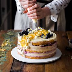 a person is decorating a cake with fresh fruit