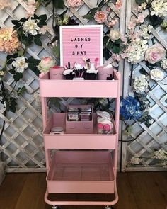 a pink cart with cosmetics and flowers on it