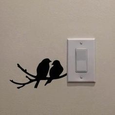 two birds sitting on a branch next to a light switch