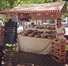 a woman standing in front of a table filled with pastries and pies on display