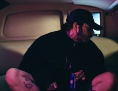 a man sitting in the back of an airplane with his legs crossed and holding a beer