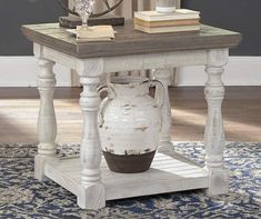 a white vase sitting on top of a wooden table next to a lamp and books