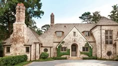 a large brick house surrounded by greenery and stone driveway with an arched doorway leading to the front door