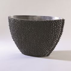 a large metal bowl with spikes on the rim and bottom, sitting on a white surface