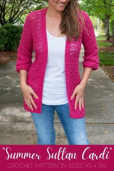 a woman wearing a pink crochet cardigan standing on a sidewalk with her hands in her pockets