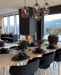 a dining room table with black chairs and plates on it, in front of large windows