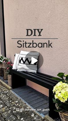 a black bench sitting in front of a building with flowers on the side and a sign that says diy sitzbank