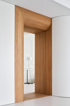 an open door leading into a room with white walls and wood paneling on the wall