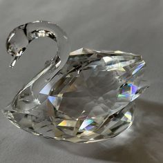 a crystal swan ornament sitting on top of a white table next to a wall