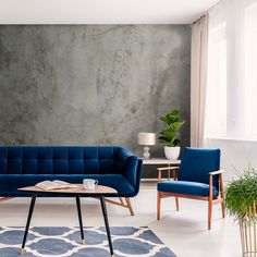 a living room with two blue couches and a coffee table in front of a concrete wall